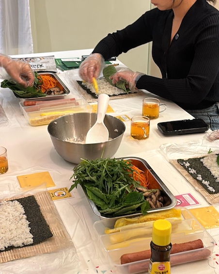 A person preparing sushi with ingredients like rice, seaweed, and vegetables on a table. 3