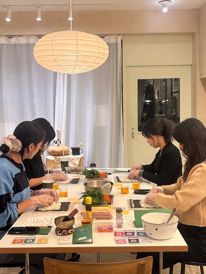 A group of people preparing food at a table with various ingredients and utensils. 1