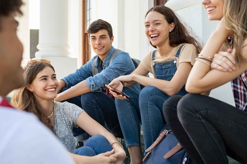 A group of people sitting on steps outdoors, engaged in conversation. 5