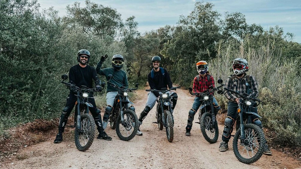 Five people on mountain bikes on a dirt trail surrounded by trees. 3