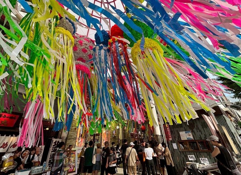 A busy street market with colorful paper decorations hanging overhead. 1