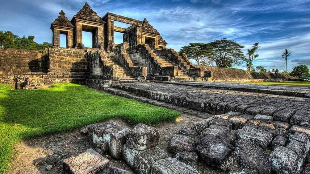 Ancient stone ruins with a large central structure and steps leading up to it. 2