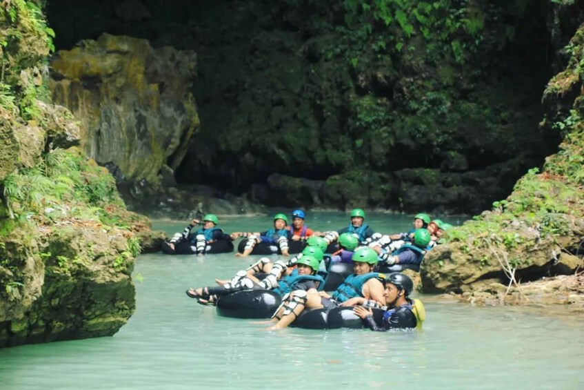 People in tubes floating down a river surrounded by rocky cliffs. 4