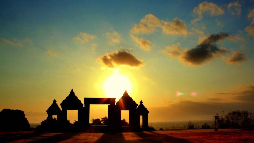 A sunset over a temple complex with multiple structures silhouetted against the sky. 1