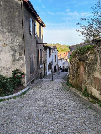 A cobblestone street flanked by historic buildings with stone walls and tiled roofs. 3