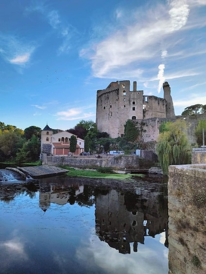 A castle with a moat, a bridge, and a small building with a red roof. 1