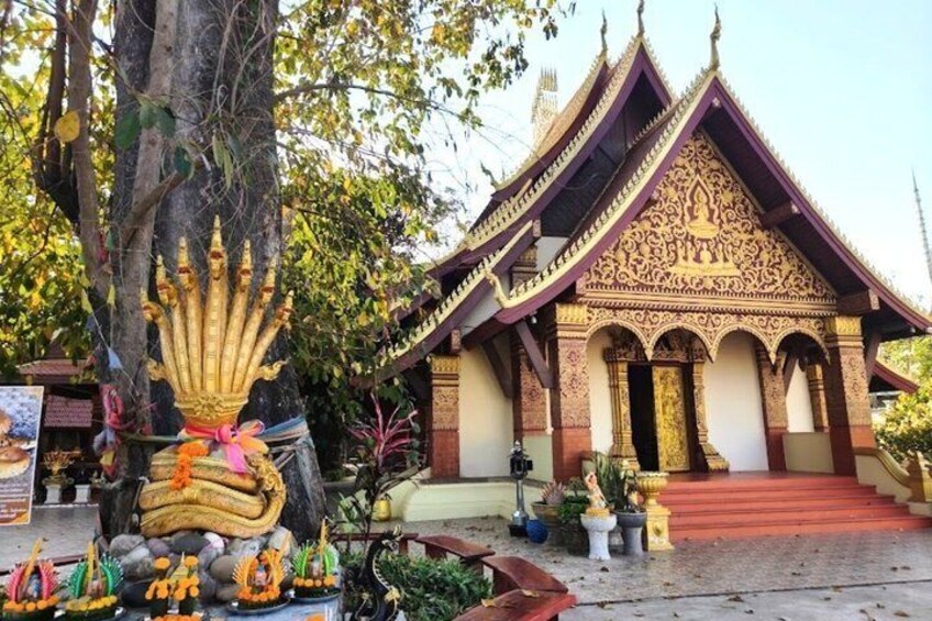 A traditional Thai temple with ornate architecture, a large golden statue, and a red staircase leading to the entrance. 4