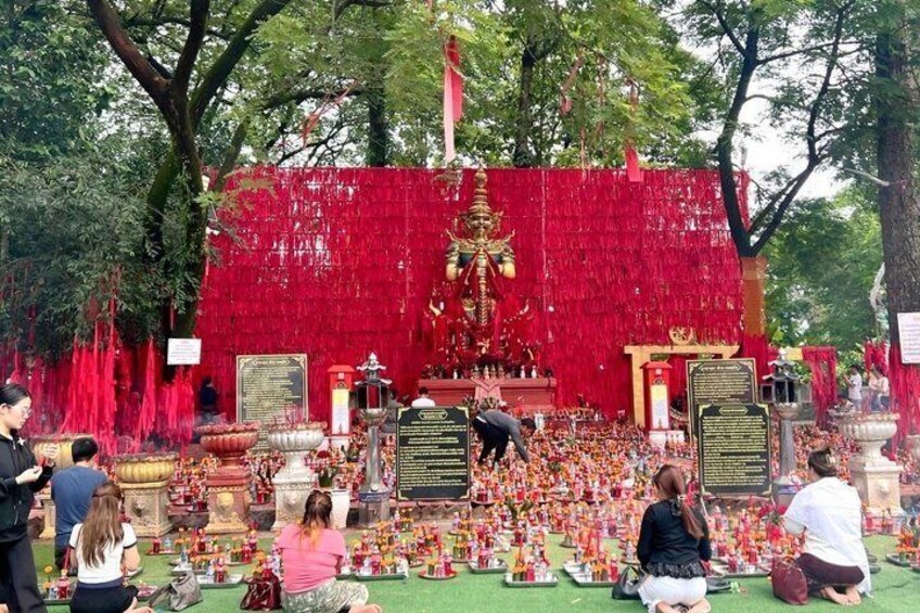 A temple with red decorations, a golden statue, and people in traditional attire. 1