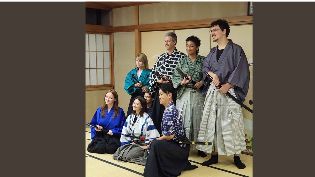 A group of people in traditional Japanese attire, some holding swords, in a room with tatami flooring and shoji screens. 2
