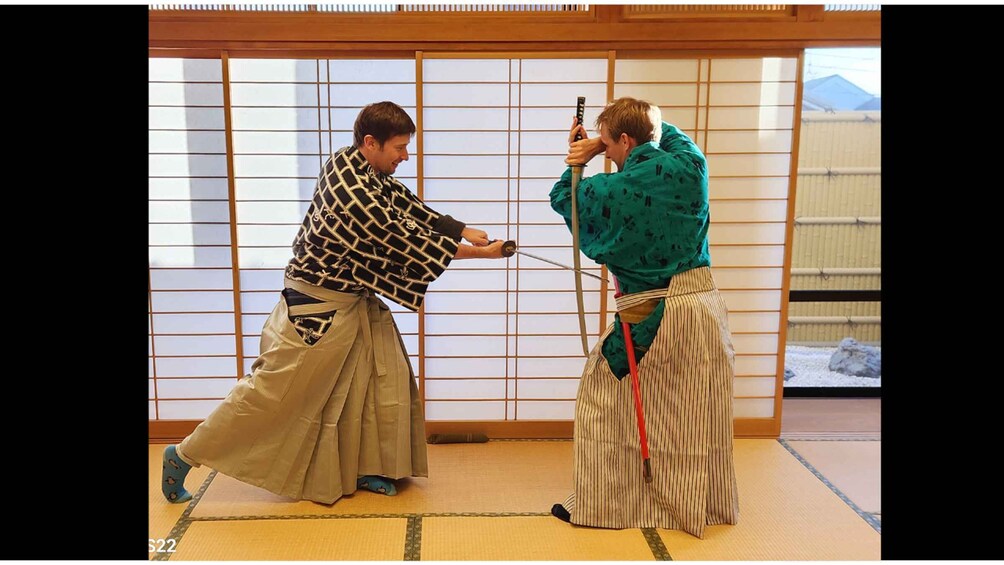 Two people in traditional attire practicing martial arts in a room with tatami mats and shoji screens. 4