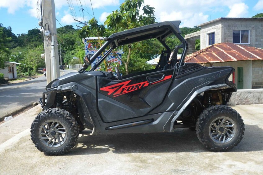 A black Ford ATV parked on a street with a building and trees in the background. 2