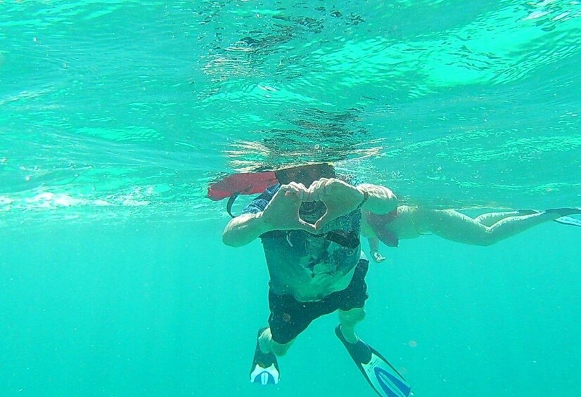 A person underwater with fins, swimming in clear turquoise water. 5