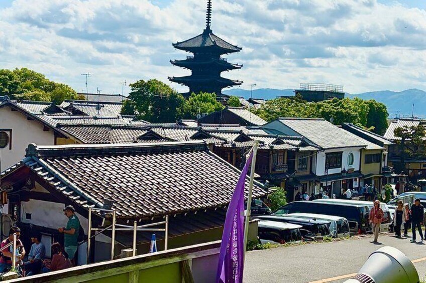 A traditional Japanese town with a prominent pagoda, a covered walkway, and a purple flag. 1