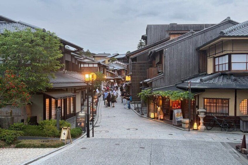 A traditional Japanese street with wooden buildings, a cobblestone path, and people walking. 5