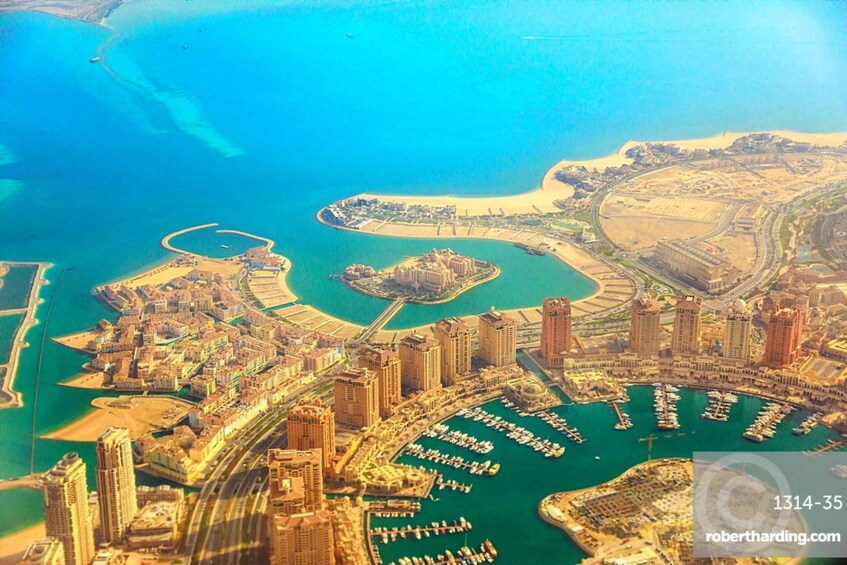 An aerial view of a coastal city with a marina, high-rise buildings, and a large body of water. 1