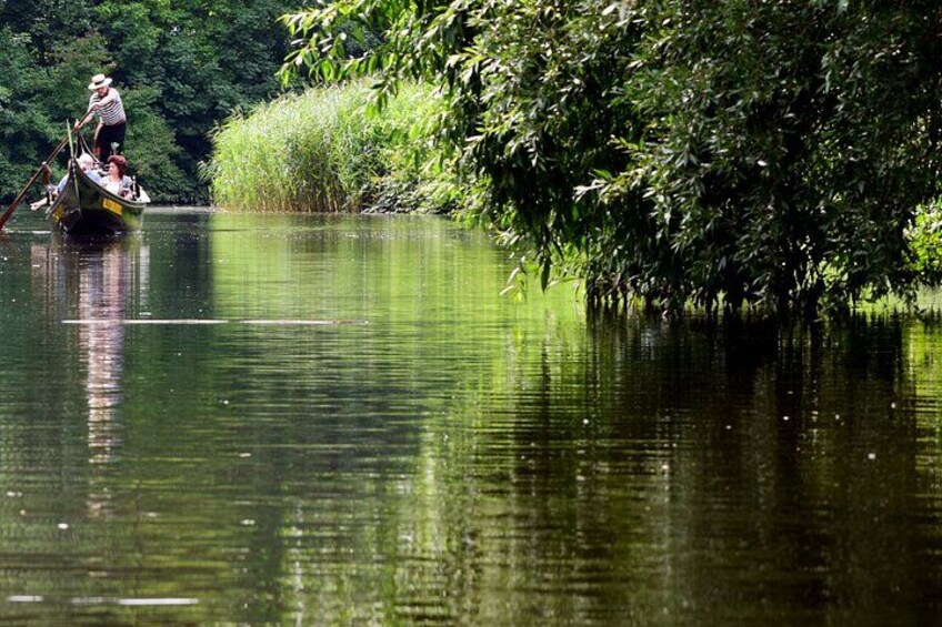 A calm river with a boat carrying people, surrounded by dense greenery. 2