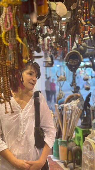 A person in a white shirt browsing a market with various items hanging above. 4