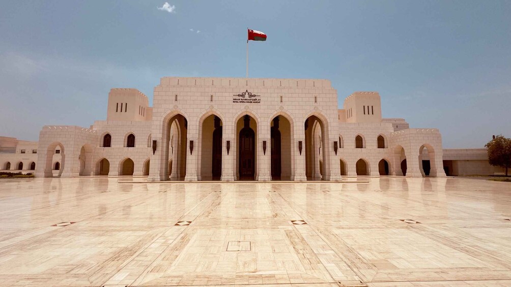 A large, white building with multiple arches and a flag on top. 3
