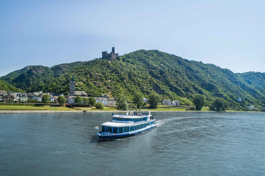 A blue riverboat on a river with a castle on a hill in the background. 3