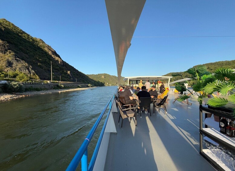 A river with a bridge, a boat with people dining, and greenery in the background. 4