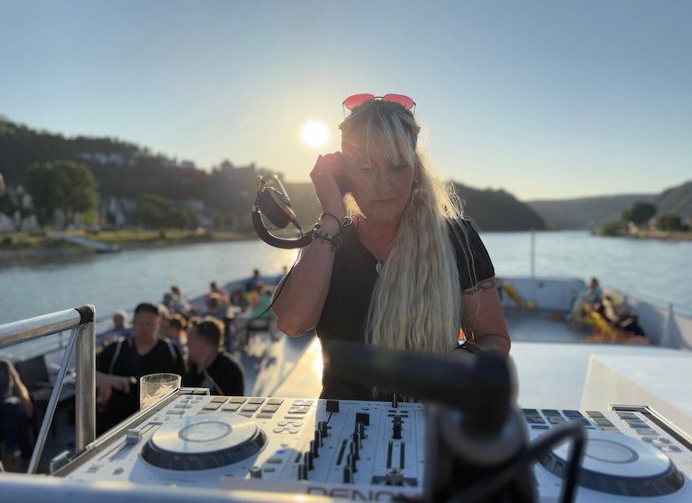 A DJ performing on a boat with a lake and hills in the background. 2