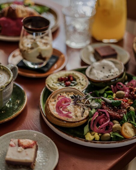 A variety of dishes on a table, including a bowl of soup with vegetables and herbs, a plate with a salad, and a glass of a yellow beverage. 3
