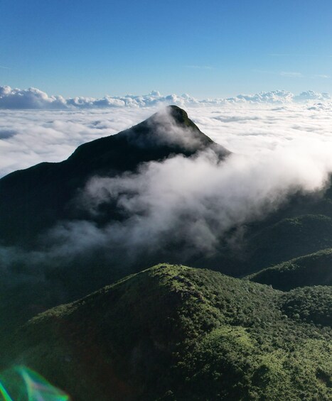 A mountain peak shrouded in clouds with lush greenery at its base. 1