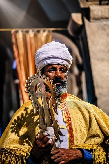 A person in traditional attire holding a ceremonial object. 1