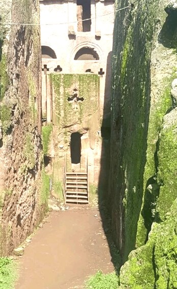 A narrow stone pathway leading to a historic building with arched windows and a central door. 5
