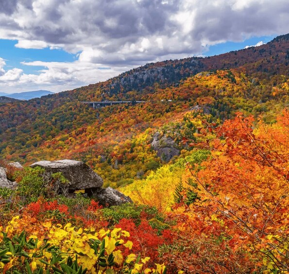 A mountainous landscape with autumn foliage, a bridge, and a rocky outcrop. 2