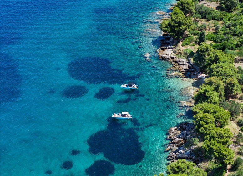 Two boats on clear turquoise waters near a rocky coastline with dense green vegetation. 2