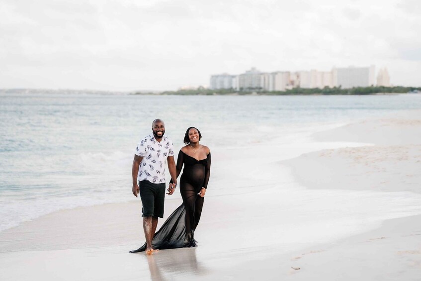 A couple walking on a beach with a cityscape in the background. 1