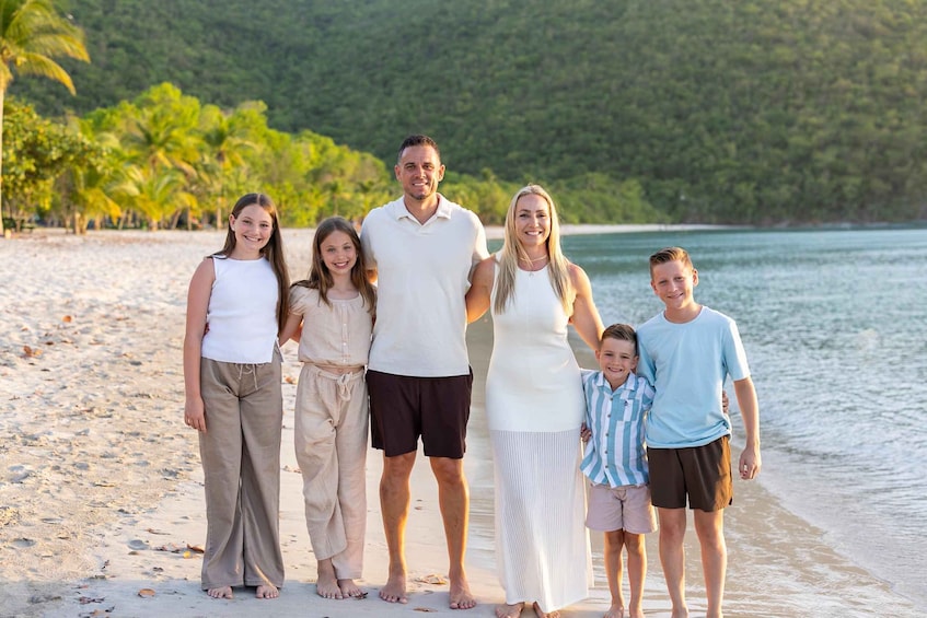 A family on a beach with palm trees and a forested hill in the background. 3