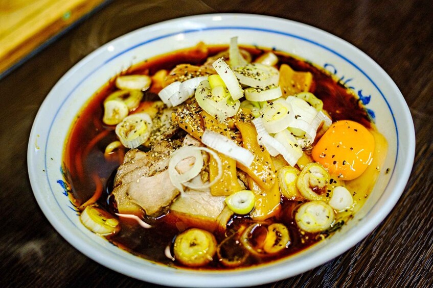 A bowl of soup with meat, vegetables, and an egg. 5