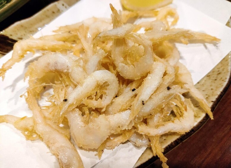 A plate of fried calamari with lemon wedges. 2