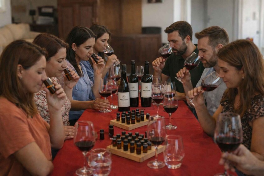 A group of people sitting around a table with wine bottles and glasses. 1