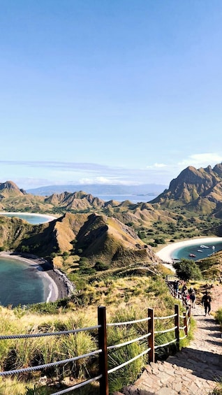 A coastal landscape with a beach, rocky hills, and a clear sky. 5
