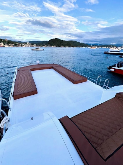 A boat deck with a white surface, brown cushioned seating, and metal railings. 3