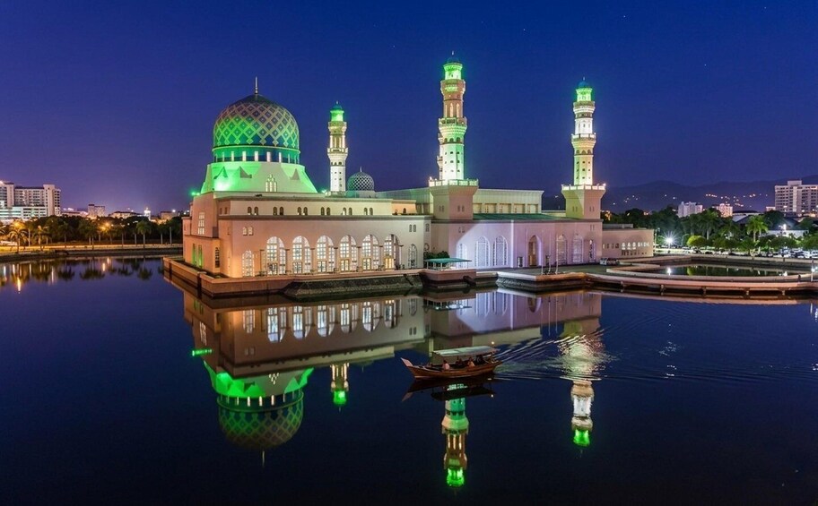 A mosque with a green dome and multiple minarets, reflecting on calm water with a boat nearby. 5