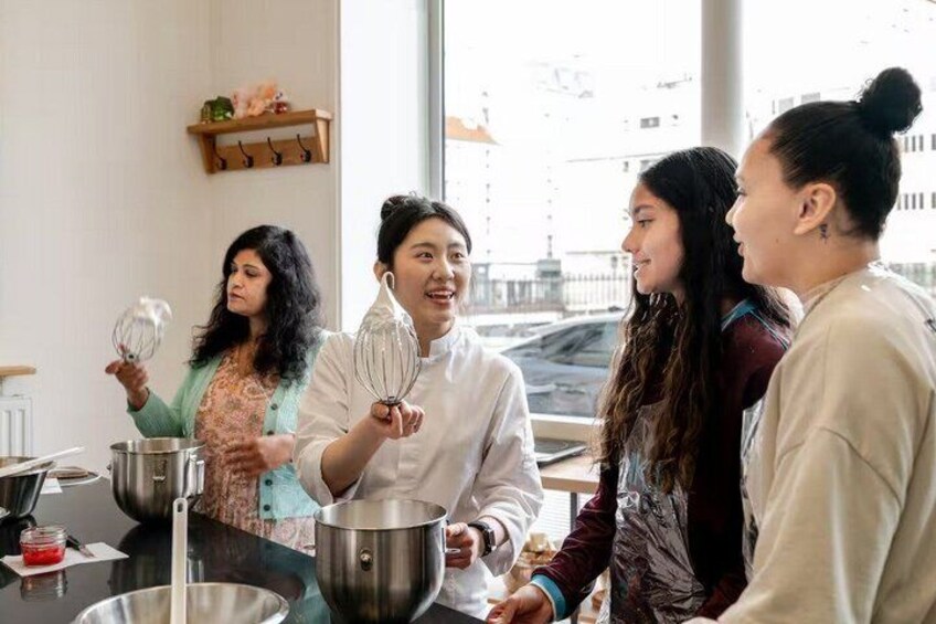 A group of people in a kitchen, some holding whisks and others with bowls, suggesting a cooking activity. 3
