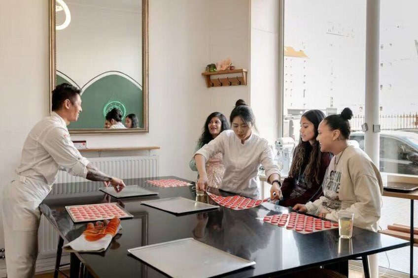 A group of people in a kitchen setting, some preparing food on a grill. 2