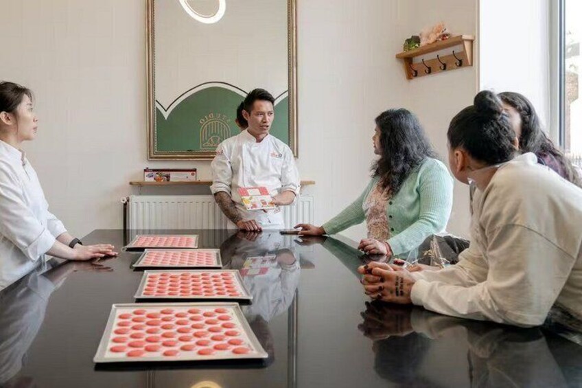 A meeting with a chef and four individuals around a table with pastries. 4