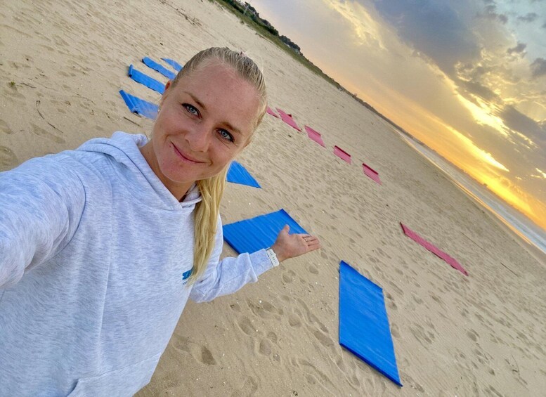 A person on a beach with blue and pink beach mats and footprints in the sand. 4