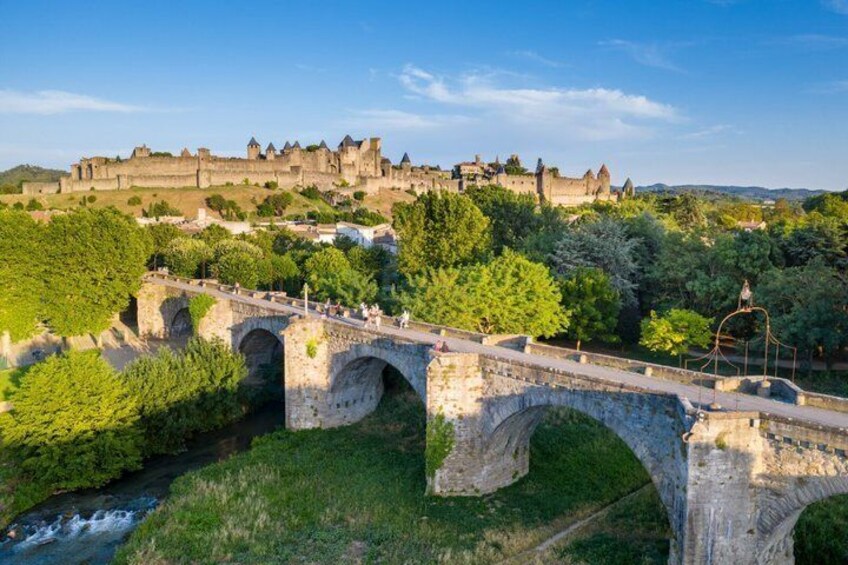A stone bridge over a river, a castle in the background, and lush greenery. 3