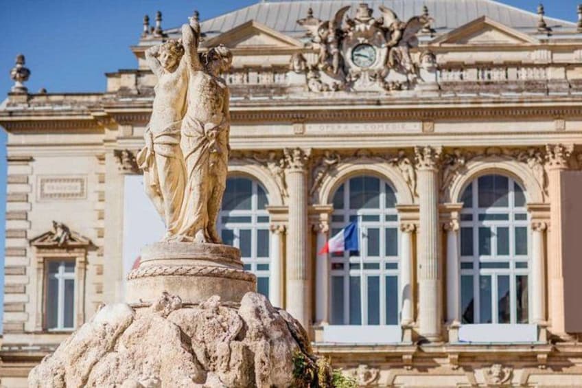 A classical statue on a pedestal in front of a grand building with columns and a clock. 2