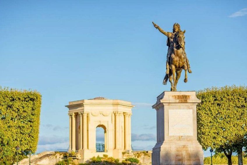 A statue of a historical figure on horseback, a classical arch monument, and neatly trimmed hedges. 5