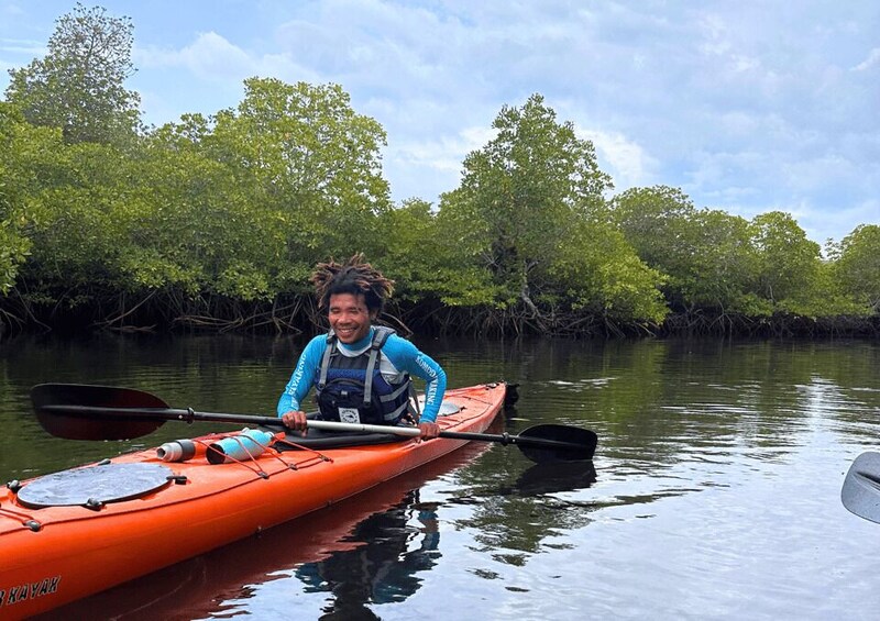A person in a kayak on calm water with dense mangrove trees in the background. 2