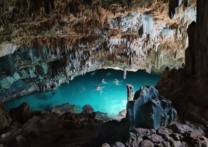 A cave with a turquoise pool and stalactites. 1