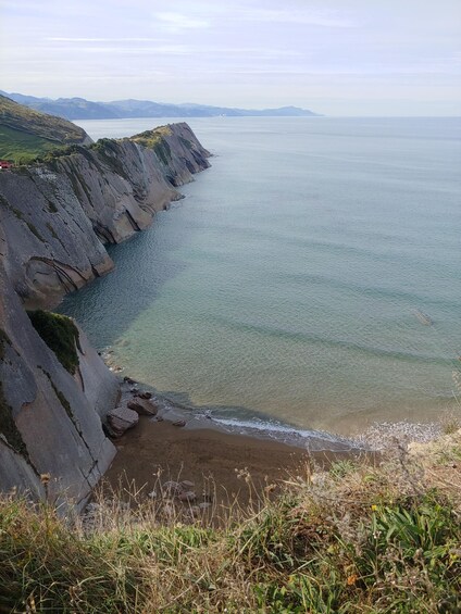 A coastal landscape with cliffs, a beach, and a calm sea. 4