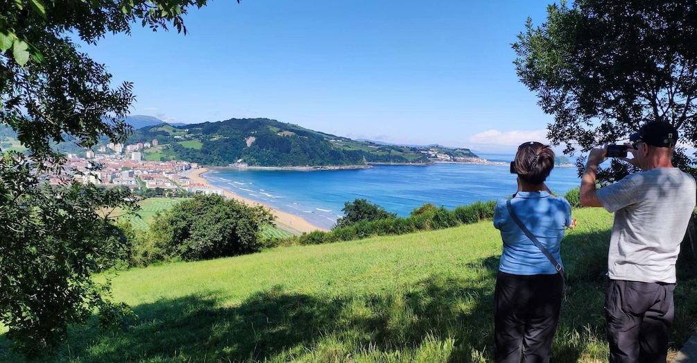 A coastal landscape with a beach, a city in the background, and hills. 1